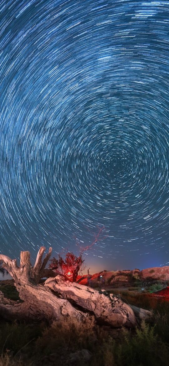 星露谷物语矿洞探索界面截图，昏暗的岩壁间点着火把，角色挥动镐子敲向铜矿脉，体力条显示在屏幕左上角